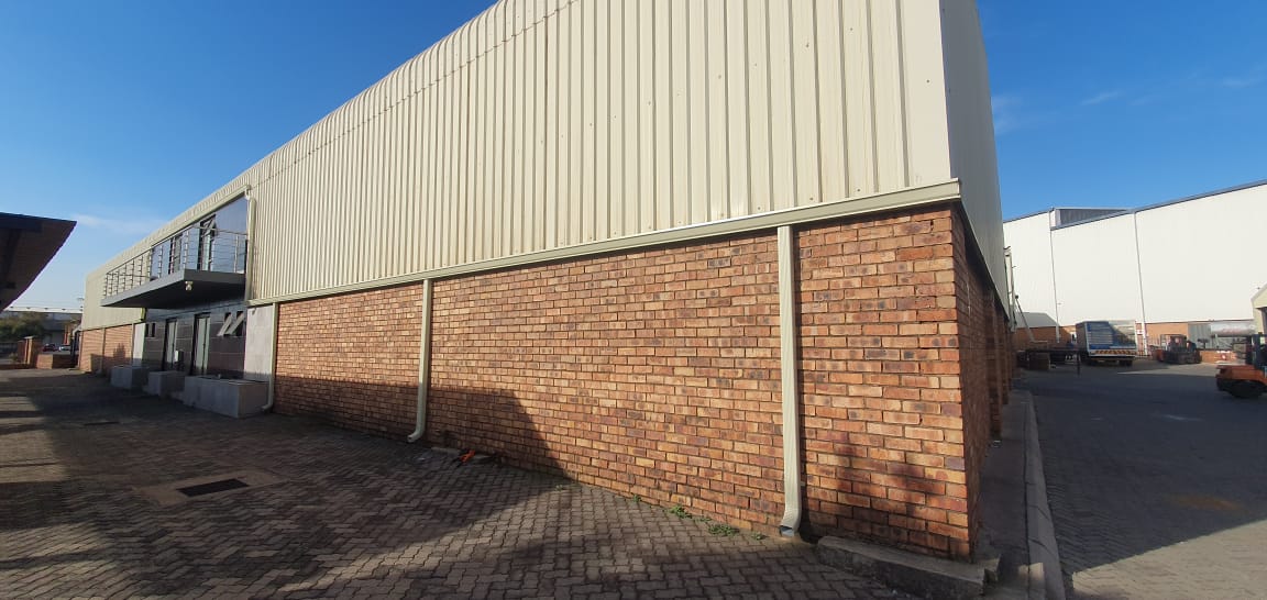 Colour matched gutter and downpipe on a commercial building with brick base